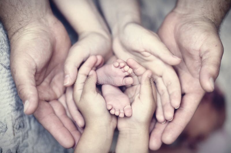 Mani di padre, di madre, di figlia, di mantenere piccoli piedi del bambino.