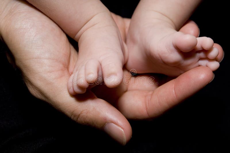 Matka drží její novorozence baby nohy v rukou.