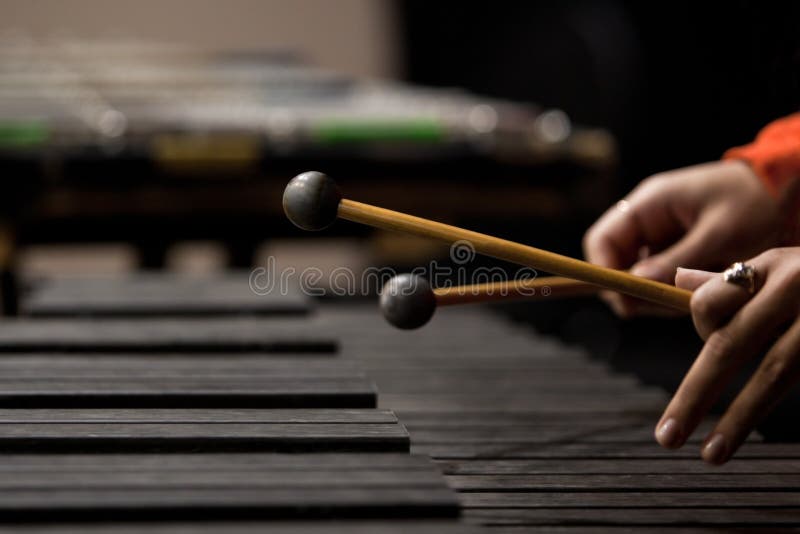 Hands of the girl playing the xylophone in dark colors