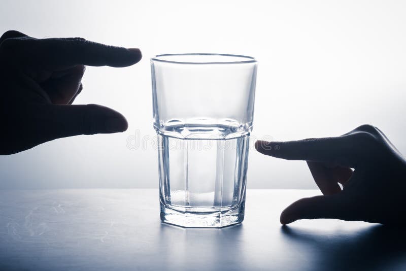 Hands measure on glass that has an empty part and left water, glass half full attitude concept, crisis and opportunity point of view. Hands measure on glass that has an empty part and left water, glass half full attitude concept, crisis and opportunity point of view