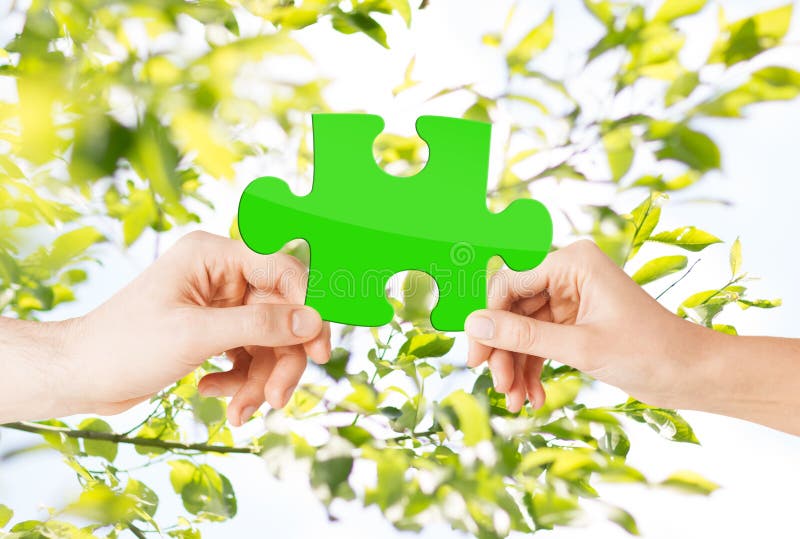 Hands with green puzzle over natural background