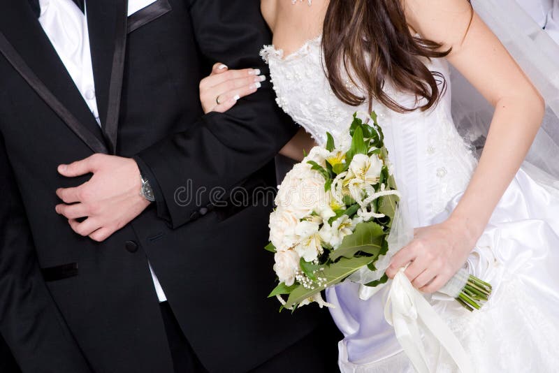 Hands of a groom and a bride with a flower bouquet