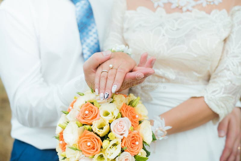 Hands of groom and bride with wedding rings and flowers roses. concept of love and marriage