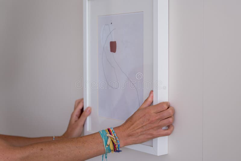 Hands Hanging an Abstract Framed Painting on the Gray Wall Stock Image