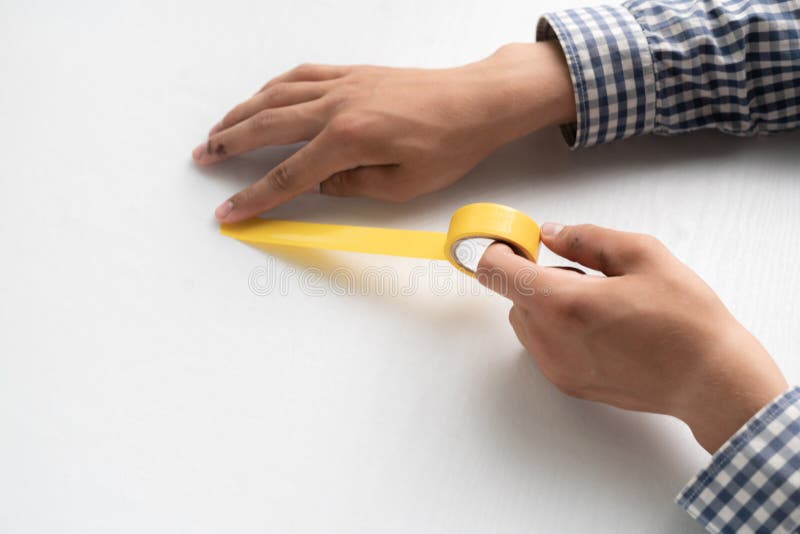 Hands Holding an Adhesive Color Tape and Apply it To the White Surfaces