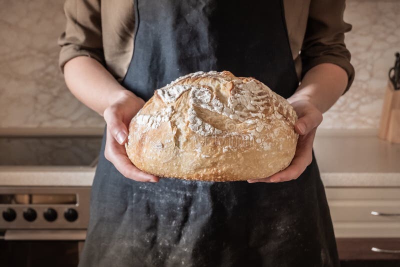 Hands holding big loaf of white bread. Female in black apron in stock photos Hands holding big loaf of white bread. Female in black apron in stock photos