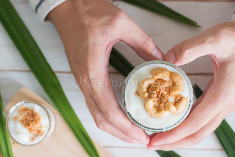 Hands holding Healthy meal made of granola in glass, Yogurt and cornflakes Decorate food with Cashew Nut