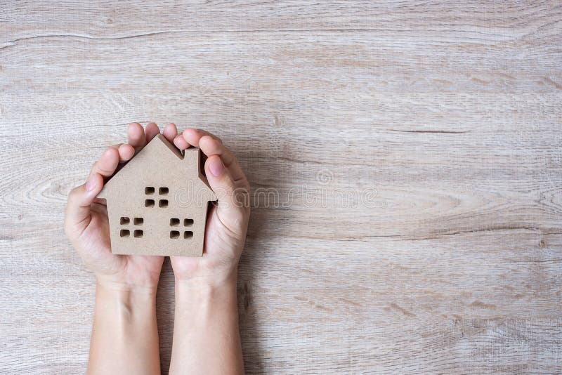 Hands holding house model on wood table background with copy space. Financial, money, refinance, Real estate and new home concept stock photos