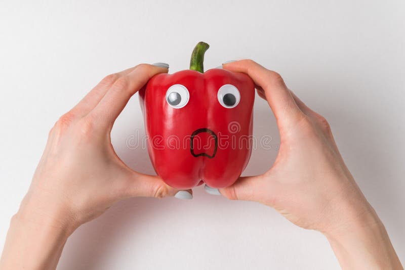 Hands Holding Large Red Pepper with Funny Scared Face. Pepper with