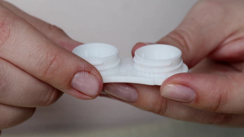 Hands holding open contact lens container. close-up of white plastic lens case stock video footage