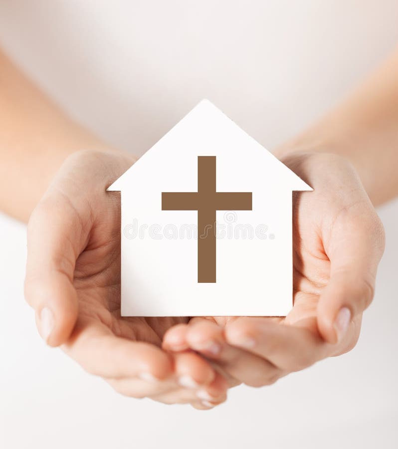 Hands holding paper house with cross symbol