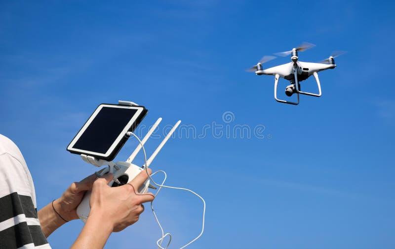 Hands holding a remote control drone camera while flying in the stock photography