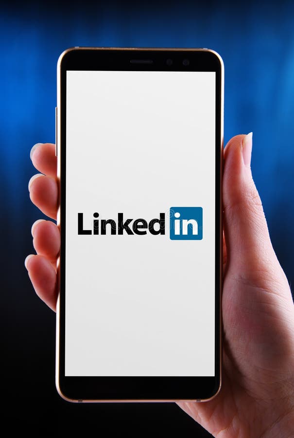 Hands holding smartphone displaying logo of LinkedIn