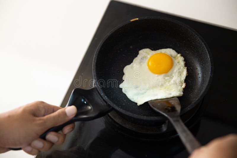 Hands holding spatula to stir fry scrambled eggs