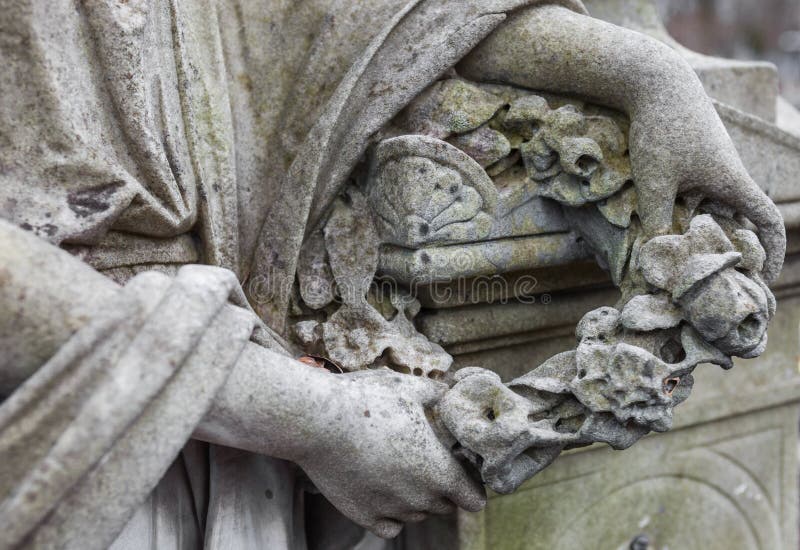 Hands holding the wreath. Old cemetery sculpture.