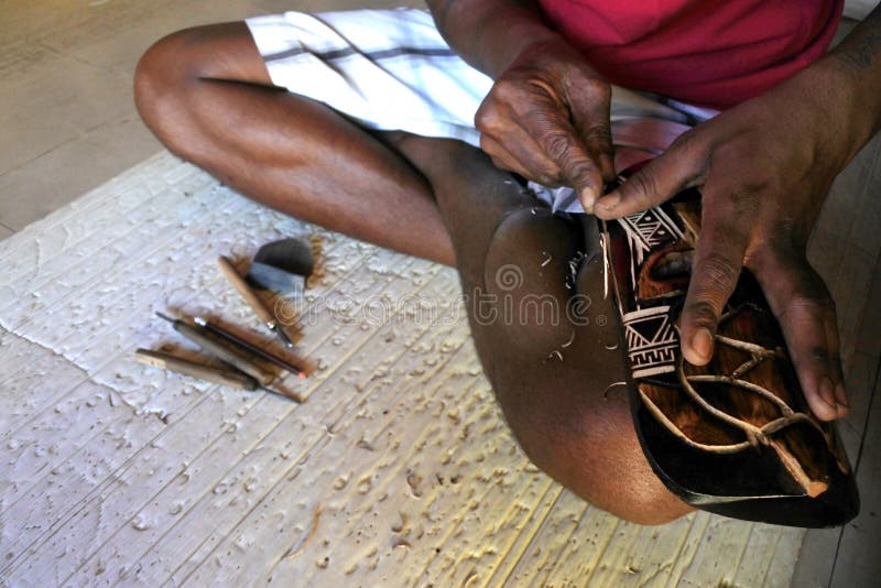 Hands of Indigenous Fijian man wood carving a sea turtle