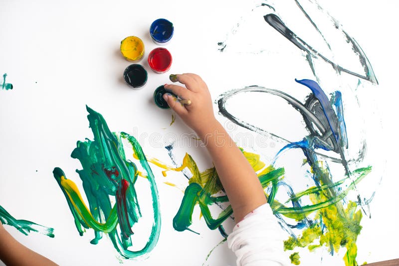 Hands of a little boy painting with watercolors on white paper sheet. Little boy with a brush and paints.  Back to school concept