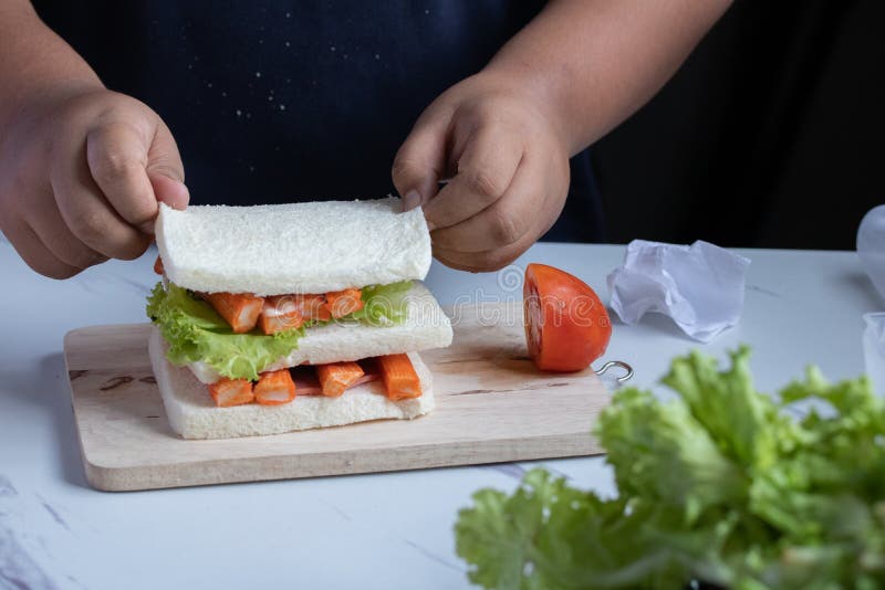 Hands are Making Crab Sticks, Bread and Tomato Sandwiches. a Healthy