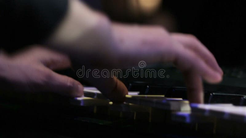 Hands of man playing keyboard in night club at show