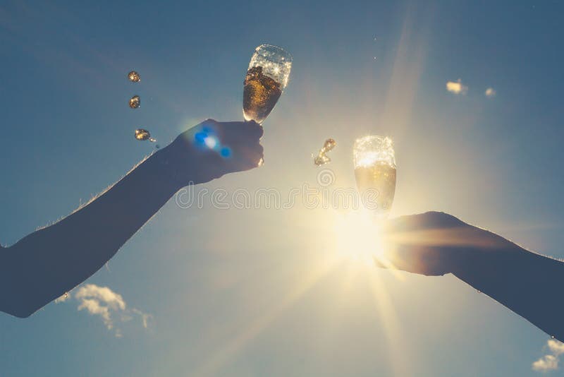Hands of man and woman clink wineglasses of sparkling white wine