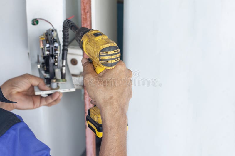 Hands of a Mechanic Holding a Automatic Screwdriver To Fix the Vending