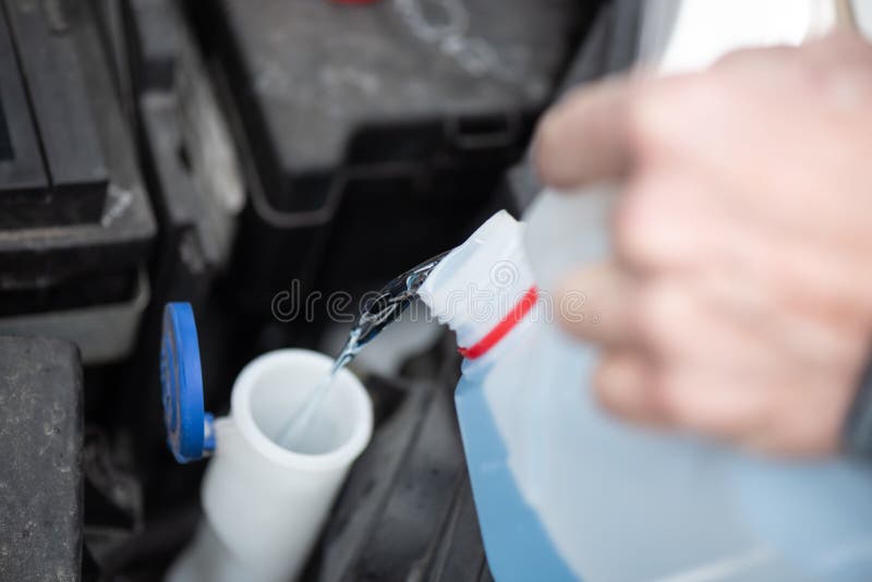 Hands of Mechanic Pouring Windshield Washer Fluid in a Car Stock Photo