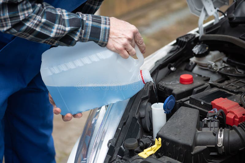 Hands of Mechanic Pouring Windshield Washer Fluid in a Car Stock Photo
