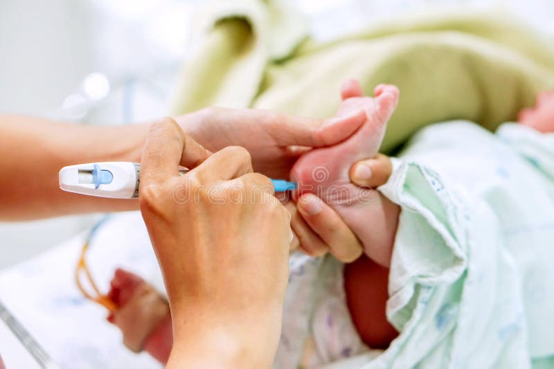 Hands of pediatric nurse holding and using Accu-Chek Fastclix needle pen for blood and glucose check stab on sick newborn baby