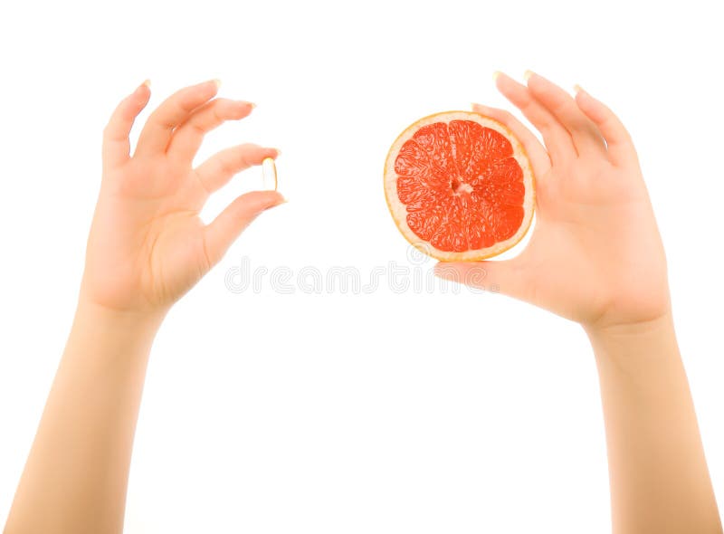 Hands with piece of grapefruit and capsules