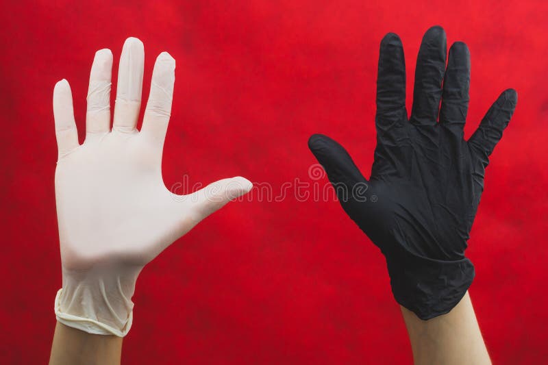 Hands raised up in protective gloves. one hand in black glove, other in white. gesturing hands in medical gloves on a red royalty free stock images Hands raised up in protective gloves. one hand in black glove, other in white. gesturing hands in medical gloves on a red royalty free stock images