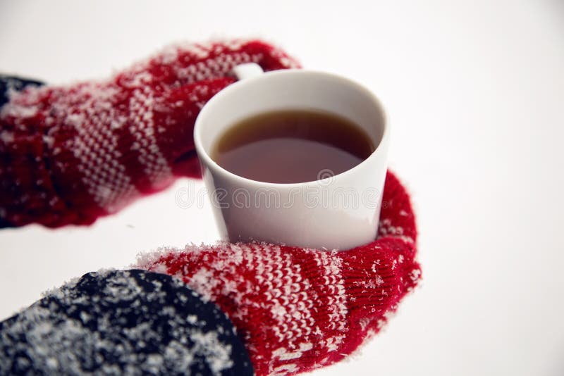 Hands in red mittens holding a mug of tea. Cold, glove.