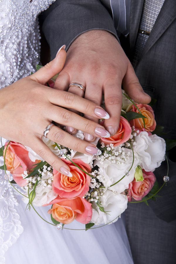 Hands and rings on wedding bouquet