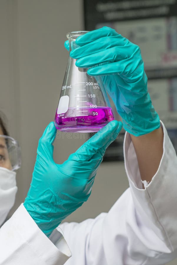Hands in Safety Glove Holding Test Glass with Chemical Inside Stock