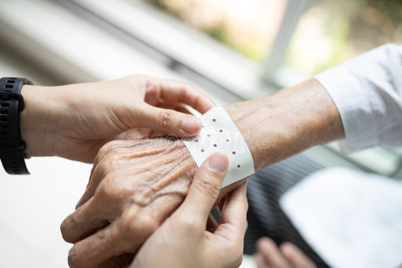 Hands of senior with analgesic sheet,chinese plaster to stick on the wrist of the old elderly to relieve muscular pain,plaster