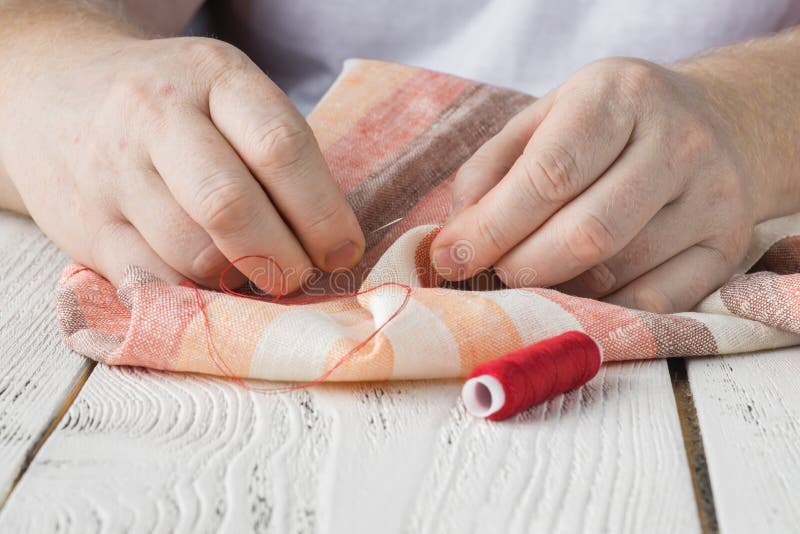 Hands Sewing Fabric with Needle at Seamstress Workplace Stock Photo