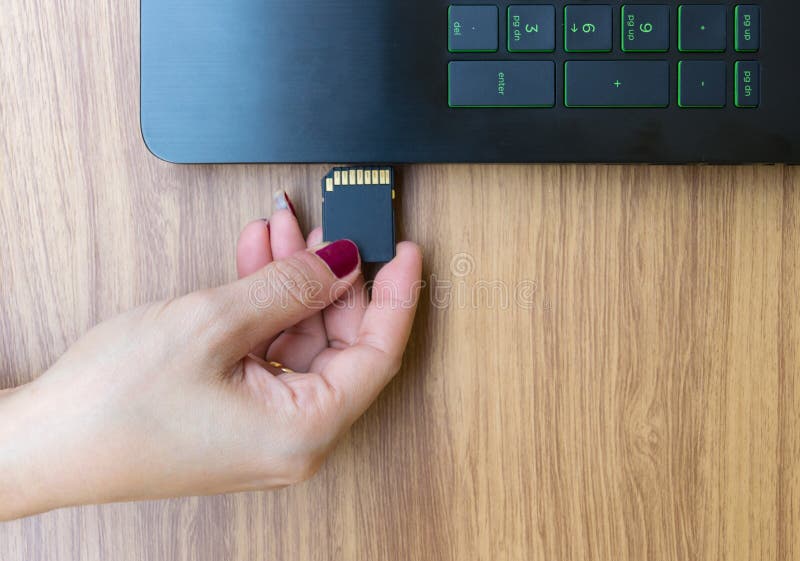 Hands show memory card of laptops user on working table desk. Hands show memory card user of laptops on working on the table desk