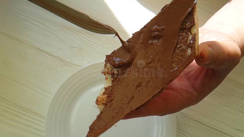 The hands smear the nutella on the cocoa bread