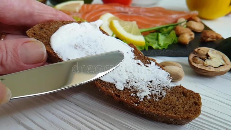 Hands smear sour cream on bread