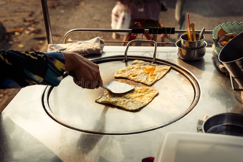 Hands of street vendor cooking Thai style sweet roti bread on steel roti pan or big flat frying pan. Hands of street vendor cooking Thai style sweet roti bread stock photography Hands of street vendor cooking Thai style sweet roti bread on steel roti pan or big flat frying pan. Hands of street vendor cooking Thai style sweet roti bread stock photography