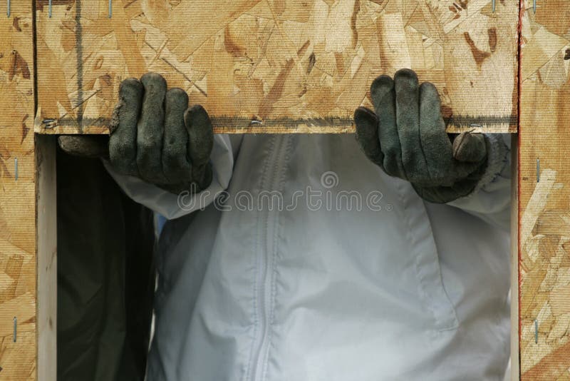 Construction worker's hands using the window opening to support a wall during installation at a construction site. Construction worker's hands using the window opening to support a wall during installation at a construction site