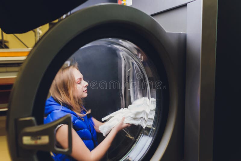 Hands To Load the Laundry in the Washing Machine at the Dry Cleaners