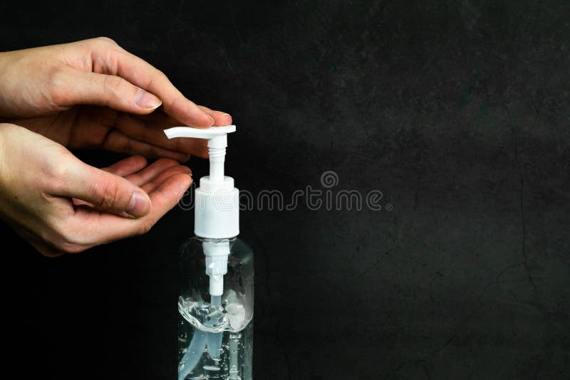 Hands using bottle of hand sanitizer, hand disinfectant on dark background. Woman preventing coronavirus infection during epidemi