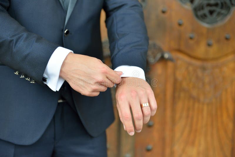 Hands of wedding groom in a elengant suit getting ready. Details of the weeding day