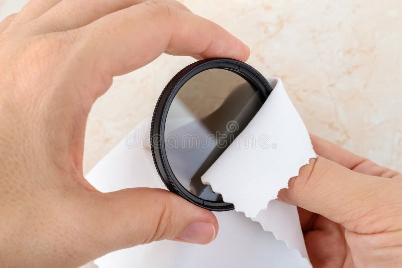 Hands Wiping a Camera Polarizing Filter with a White Microfiber Cloth. Routine Removal of Dust