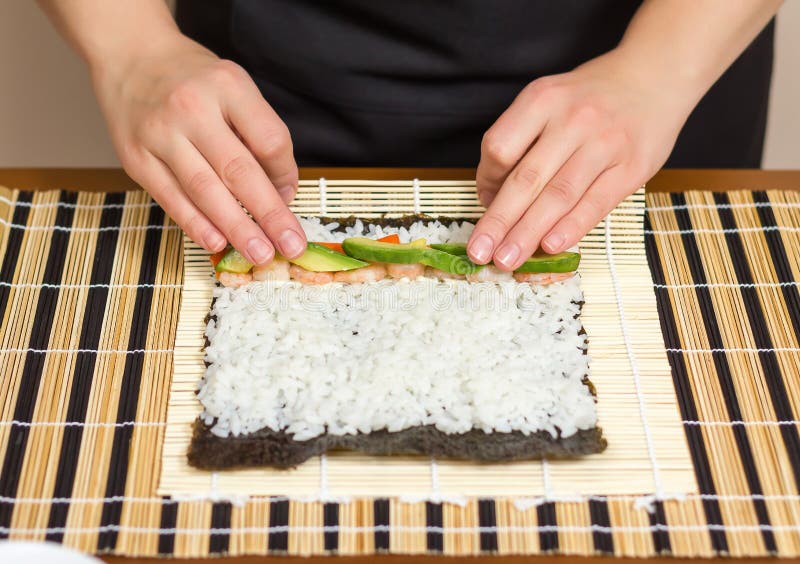 Hands of woman chef rolling up a japanese sushi stock image Hands of woman chef rolling up a japanese sushi stock image