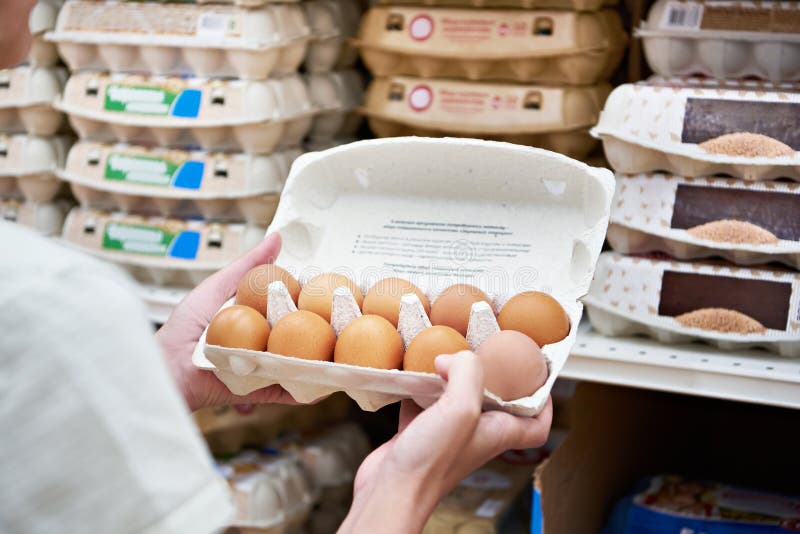 Hands with packages of eggs in store