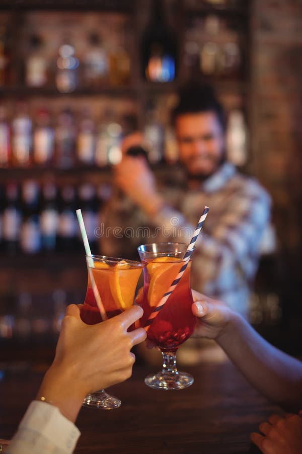 Hands of Women Toasting Their Cocktail Drinks at Counter Stock Photo