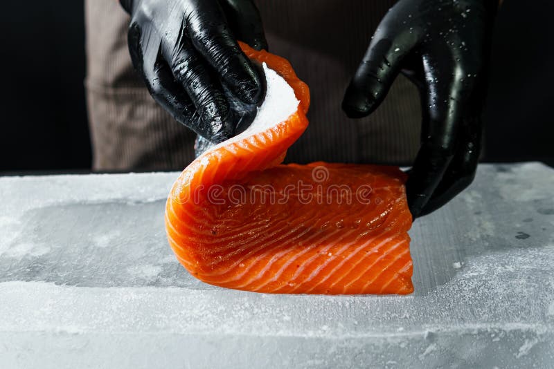 Handschließung, zubereitet zum Kochen von frischem Lachsfilet, schwarzer Hintergrund stockfoto