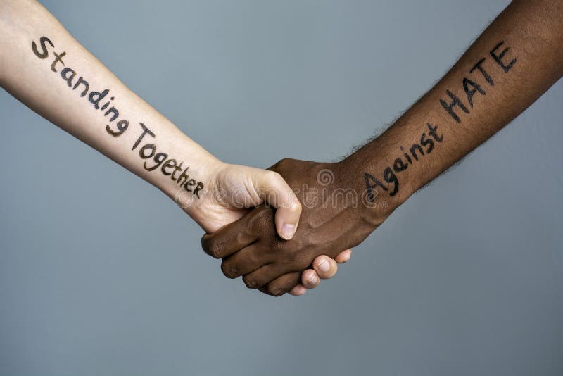 Handshake between black and white human woman and male hands with the message text Standing Together against HATE. Concept of Black Lives Matter protest against racism and police brutality.