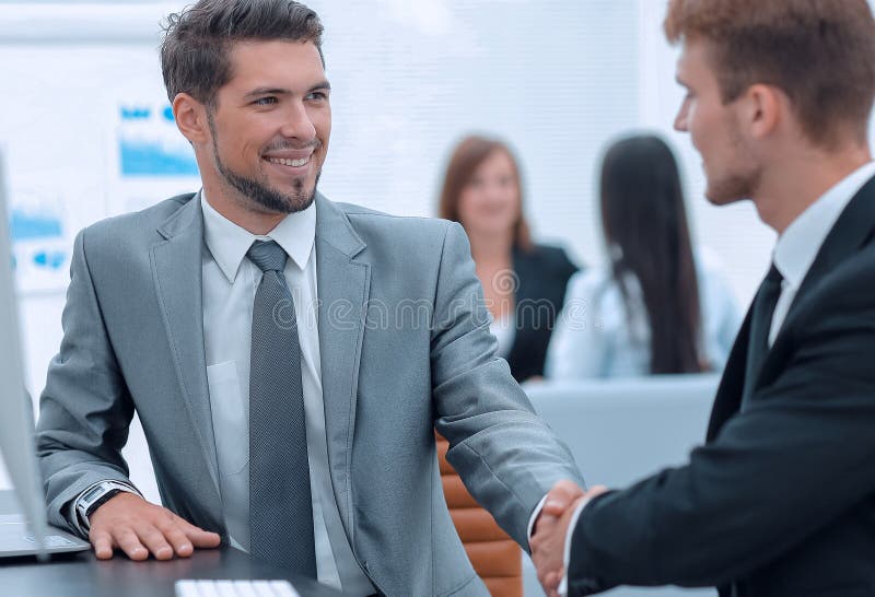 Handshake of Business Partners Sitting at a Desk. Stock Photo Image